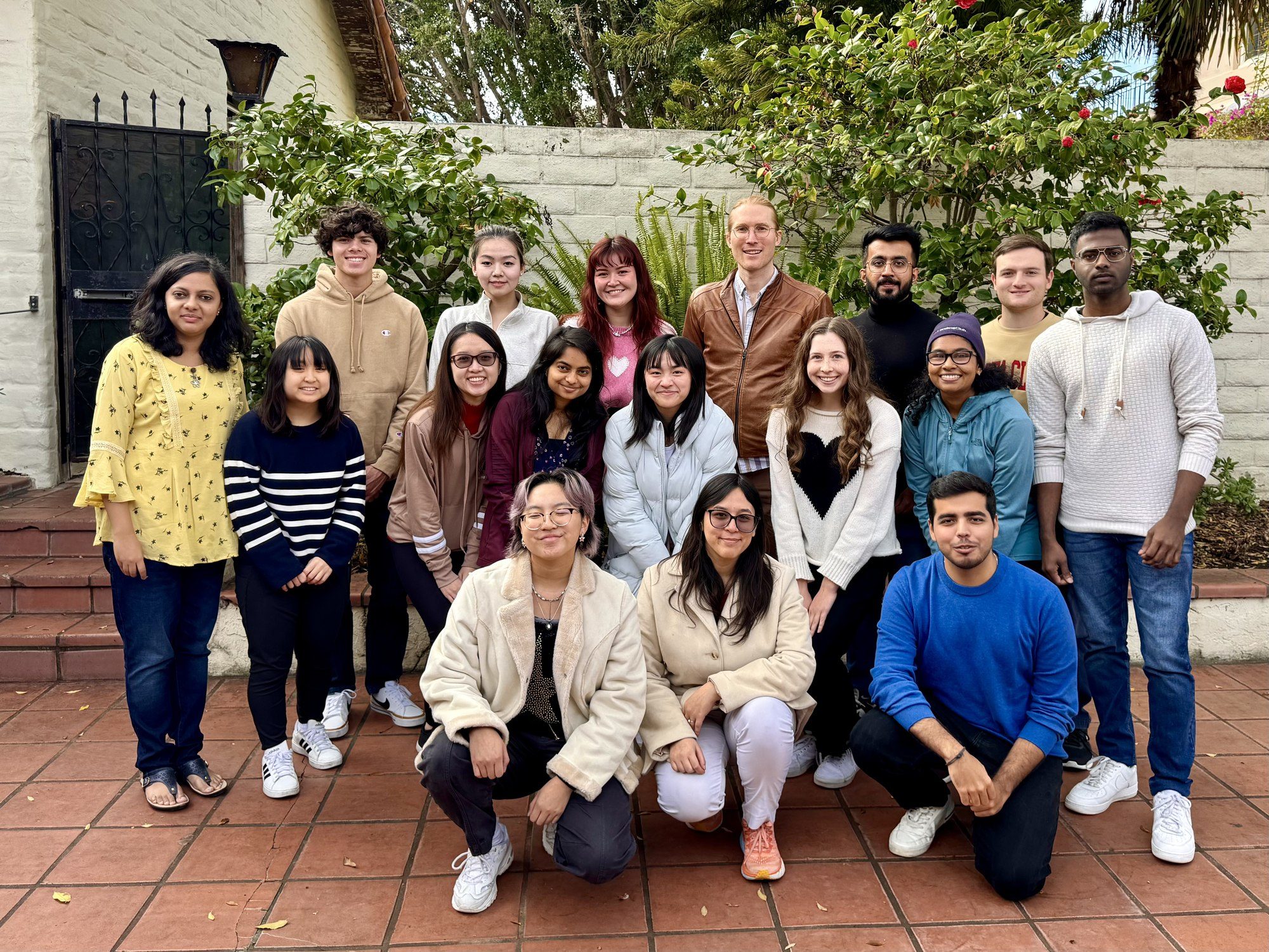 Lab members pose together in a garden courtyard.